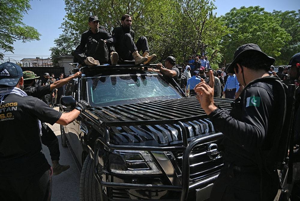 Anggota keselamatan mengawal kereta yang membawa Imran ketika beliau tiba di mahkamah di Islamabad. - Foto AFP