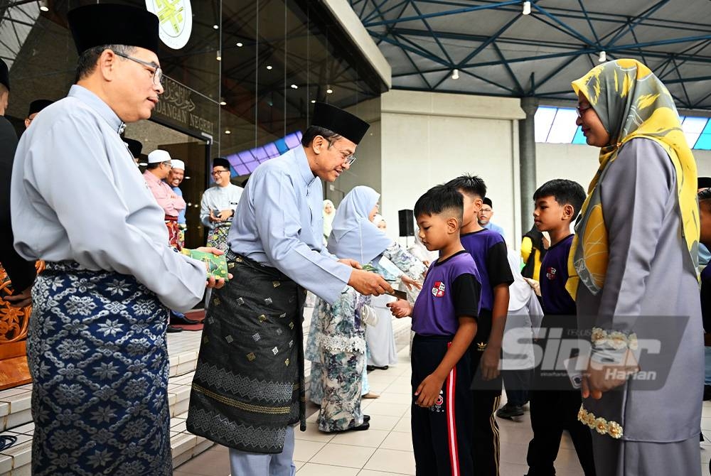 Ahmad Samsuri (dua dari kiri) bersama Setiausaha Kerajaan Negeri, Datuk Tengku Farok Hussin Tengku Abdul Jalil menyampaikan duit raya kepada kanak-kanak sempena sambutan Hari Raya Aidilfitri di Wisma Darul Iman di Kuala Terengganu, pada Rabu.