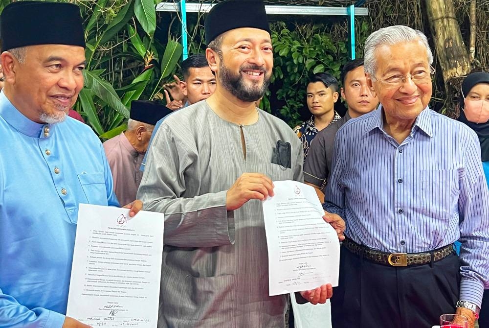 Mukhriz (tengah) menunjukkan borang Proklamasi Orang Melayu yang ditandatangani pada Majlis Rumah Terbuka Aidilfitri anjuran Pertubuhan Prihatin Kubang Pasu di Kampung Naga pada Khamis.