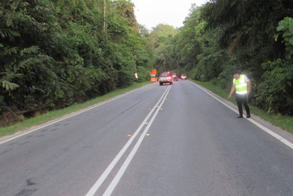 Anggota polis menunjukkan lokasi sorang lelaki maut di kilometer 14, Jalan Gua Musang-Kuala Lipis pada Khamis.