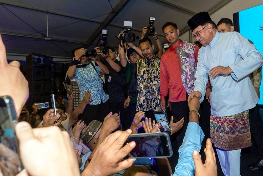 Anwar bersalaman bersama orang ramai selepas menghadiri Majlis Rumah Terbuka Malaysia Madani di pekarangan Stadium Sultan Muhammad IV malam ini. - Foto Bernama