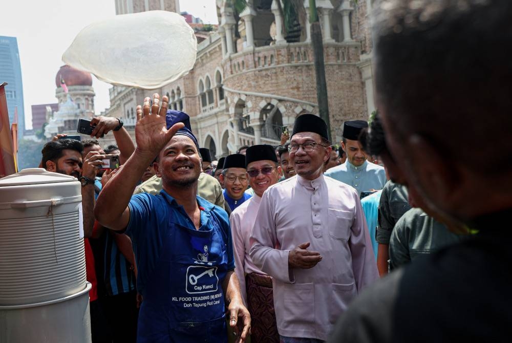 Anwar melihat aksi seorang penebar roti canai ketika mengunjungi gerai-gerai makanan pada Majlis Rumah Terbuka Aidilfitri Malaysia Madani di Dataran Merdeka hari ini. - Foto Bernama