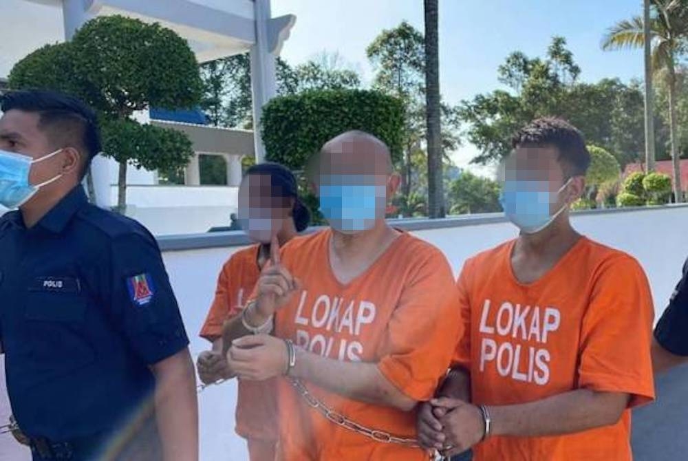 Seorang suspek kelihatan ceria ketika diiring oleh anggota polis selain sempat memberikan beberapa tanda isyarat seperti 'okey dan bagus kepada pemberita. - Foto Astro Awani