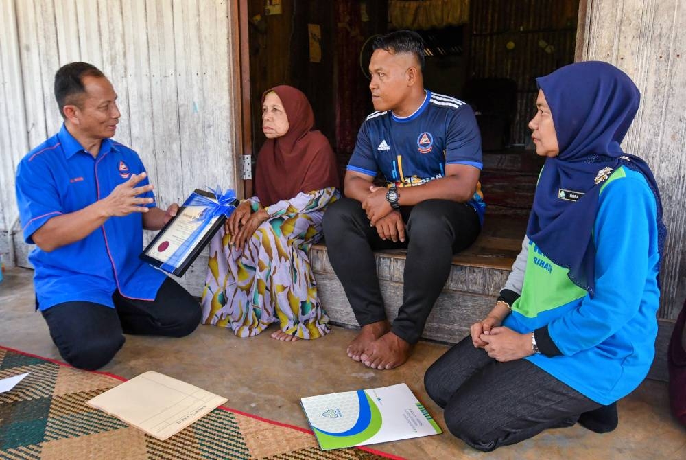 Nora (kanan) bersama Abdul Wahab (kiri) menziarahi ibu mangsa, Noriah Awang, 67, (dua, kiri) di kediamannya di Kampung Kemasin pada Ahad. - Foto Bernama