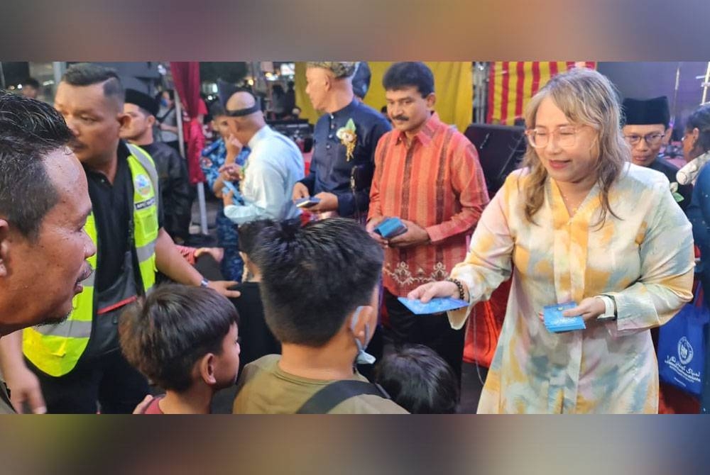 Elizabeth Wong memberikan duit raya kepada kanak-kanak yang hadir Majlis Aidilfitri DUN Bukit Lanjan pada Ahad.