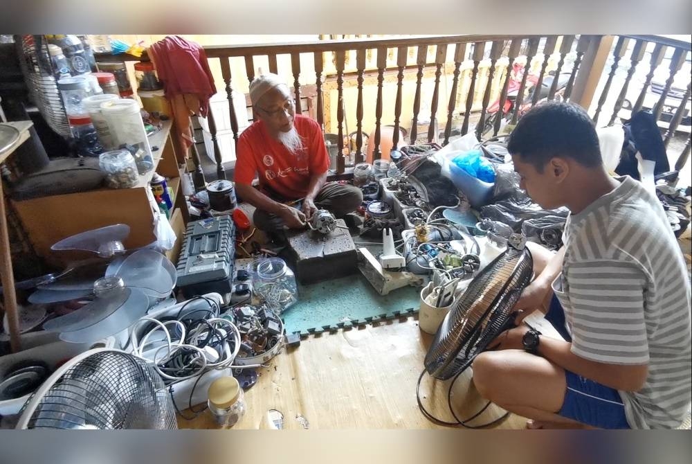 Hamid melayani seorang pelanggan yang menghantar kipas untuk dibaiki di kediamannya di Kampung Gong Kemunting, Kuala Ibai di Kuala Terengganu.