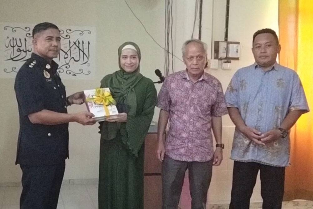 Tengku Munazirah (tengah) menyampaikan sumbangan al-Quran sempena Majlis Penyampaian Sumbangan Al-Quran kepada Sanusi di SMK Putera