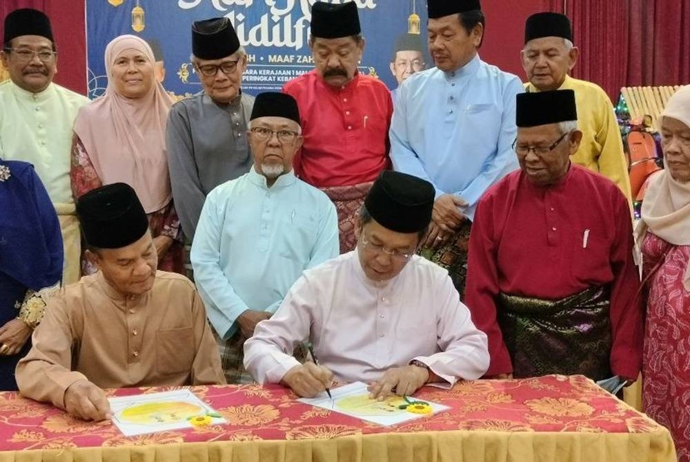 Jalaluddin (duduk, kanan) ketika menandatangani watikah pelantikan sebagai penaung Kupekmas Negeri Sembilan sambil diperhatikan oleh Omar (duduk, kiri).