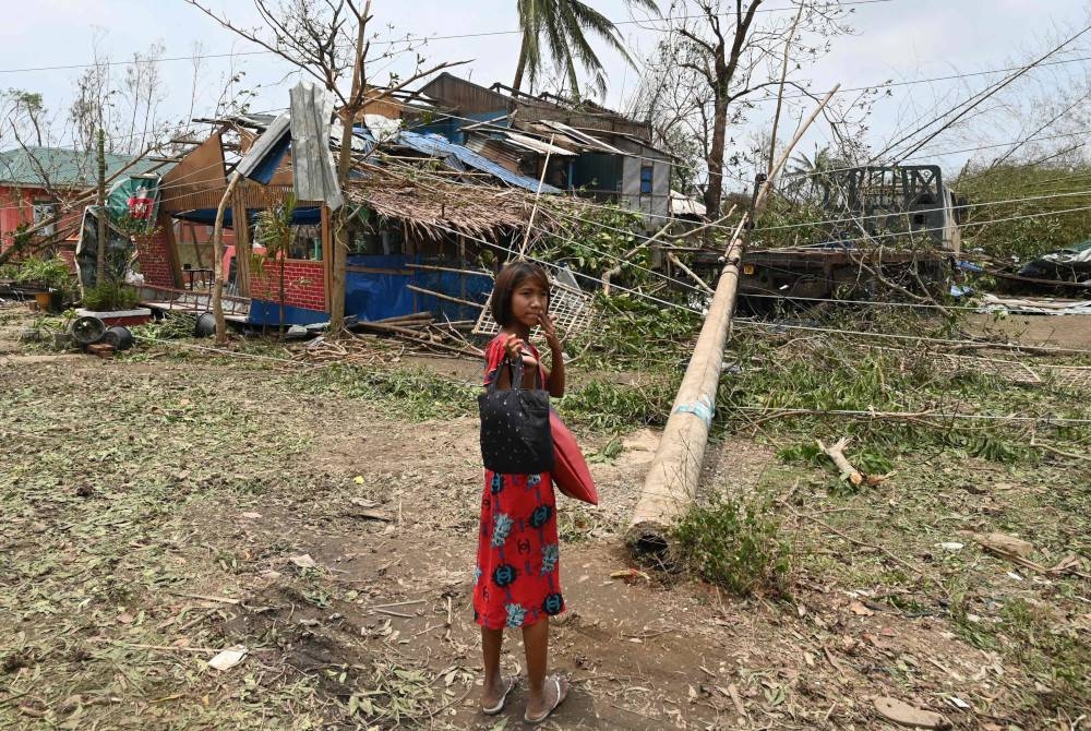 Seorang kanak-kanak perempuan berdiri di hadapan sebuah bangunan yang rosak akibat taufan Mocha di Sittwe, Rakhine, Myanmar. - Foto AFP