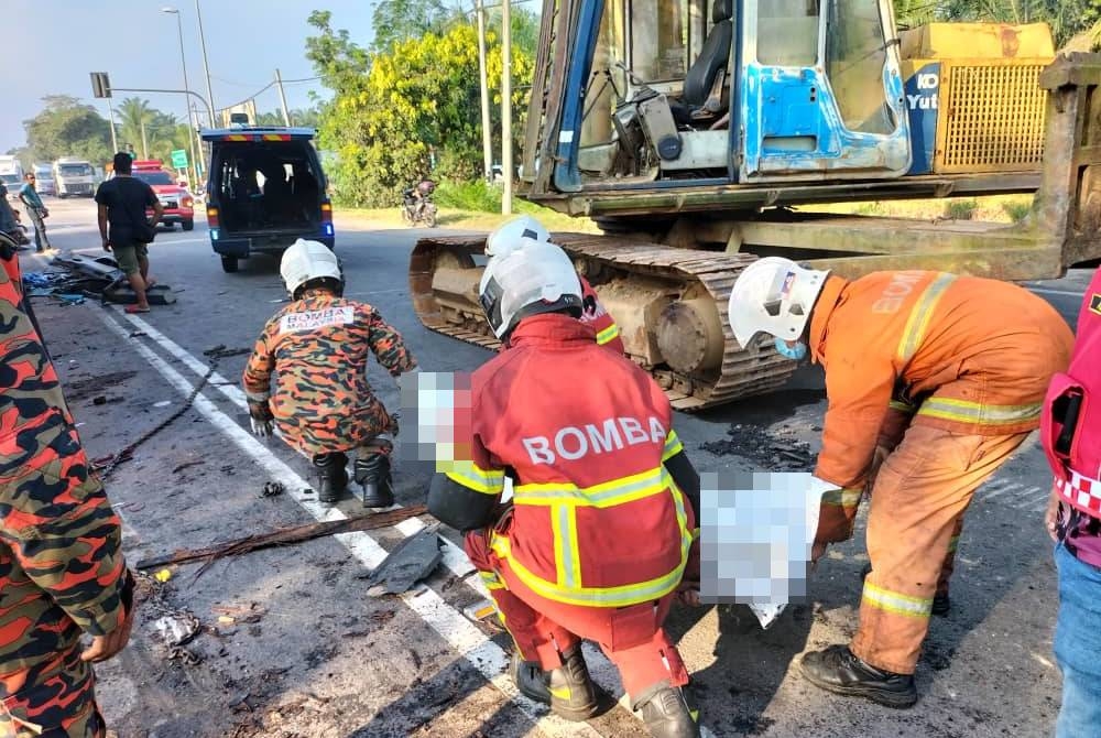 Anggota bomba mengangkat mayat pemandu yang rentung dalam kebakaran melibatkan tiga lori membawa muatan kayu balak di Kampung Temehel, Yong Peng, Batu Pahat pada Selasa.