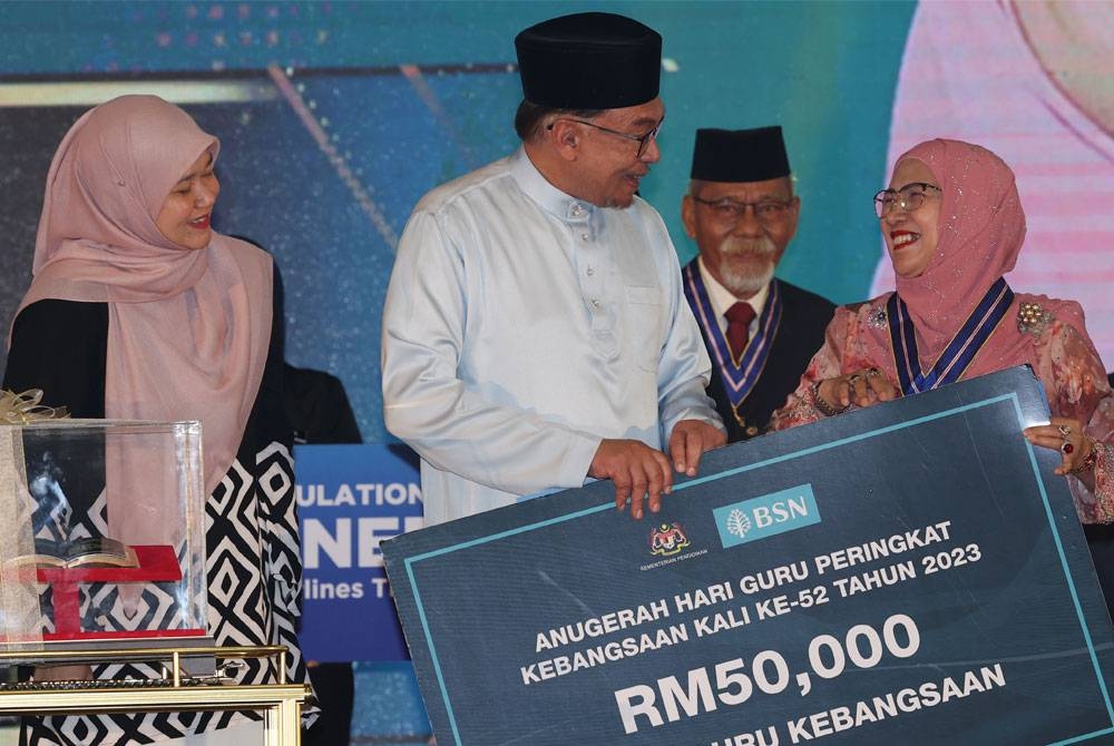 Anwar (tengah) menyampaikan Anugerah Tokoh Guru Kebangsaan 2023 kepada Datuk Seri Panglima Dr Nuinda Alias pada Sambutan Hari Guru Peringkat Kebangsaan 2023, di MITC, Ayer Keroh pada Selasa. - Foto Bernama