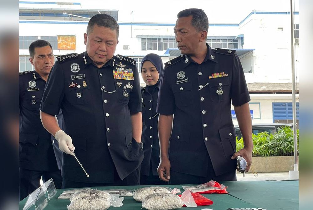 Kok Chin (kiri) menunjukkan dadah yang dirampas daripada suspek.