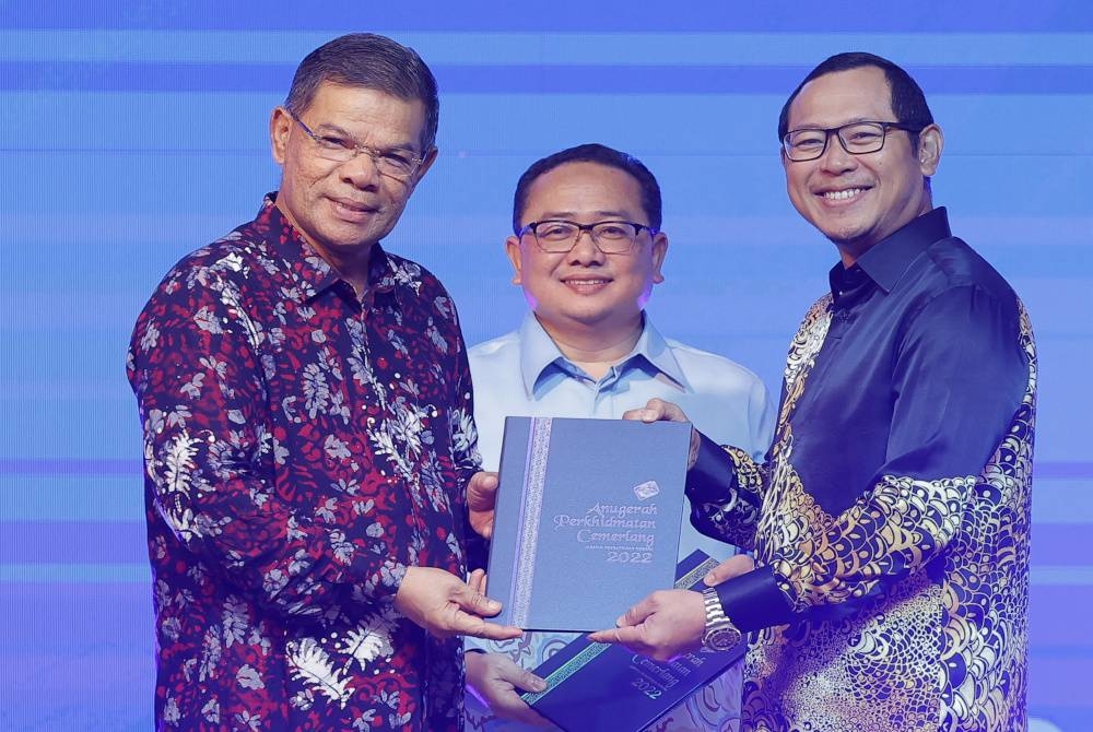 Saifuddin Nasution menyampaikan anugerah perkhidmatan cemerlang kepada Pegawai Jabatan Pendaftaran Negara (JPN), Mohd Zaaba Abd Hamid (kanan) pada Majlis Anugerah Perkhidmatan Cemerlang dan Persaraan JPN di Puspanitapuri pada Khamis. - Foto Bernama