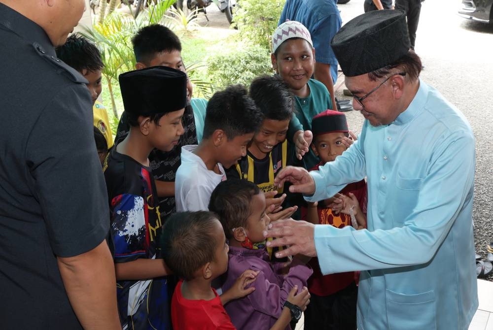 Anwar beramah mesra dengan kanak-kanak selepas menunaikan solat Jumaat di Masjid Dr Mohamad Eusuff Teh, di Pedas Hilir pada Jumaat. - Foto Bernama