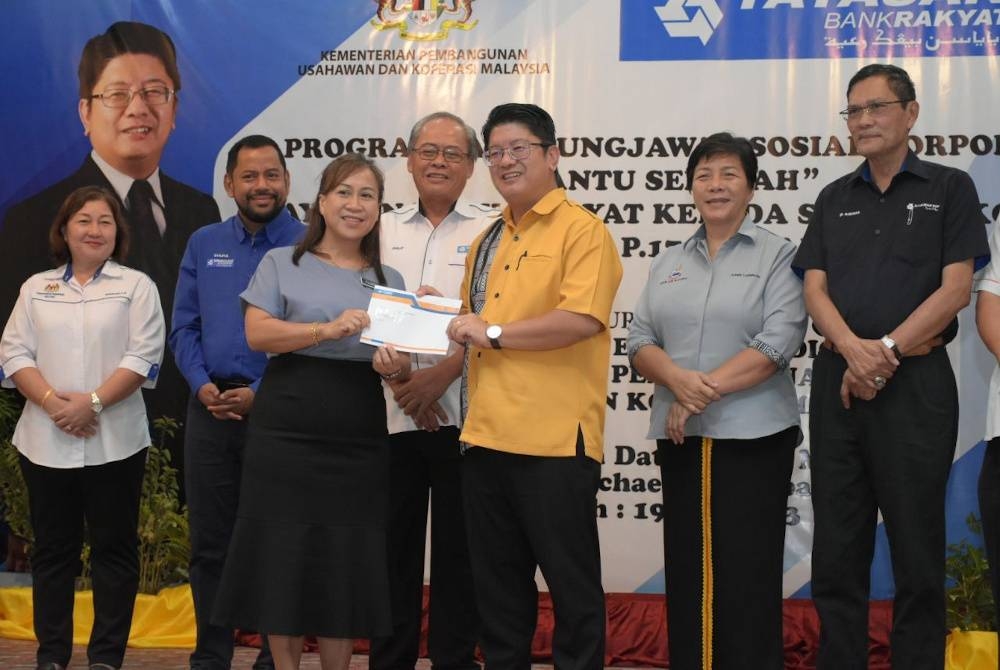 Ewon menyampaikan sumbangan kepada wakil sekolah pada Program CSR Bantu Sekolah YBR di Dewan SM St Micheal Penampang.