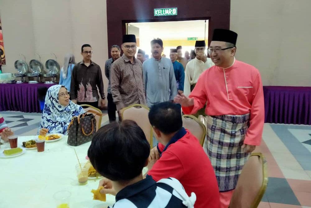 Lih Kang (berdiri, kanan) menyantuni orang ramai yang hadir ketika Rumah Terbuka Aidilfitri Parlimen Tanjung Malim di Dewan Rajawali, Felda Residence Trolak pada Sabtu.