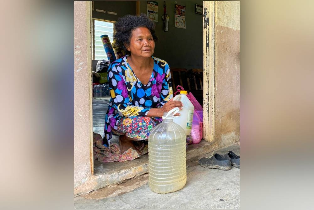 Amoi menunjukkan botol air yang digunakannya bagi menyimpan air ekoran ketiadaan air untuk kegunaan harian di rumahnya di Kampung Pasir Linggi, Pos Lebir. - Foto Bernama