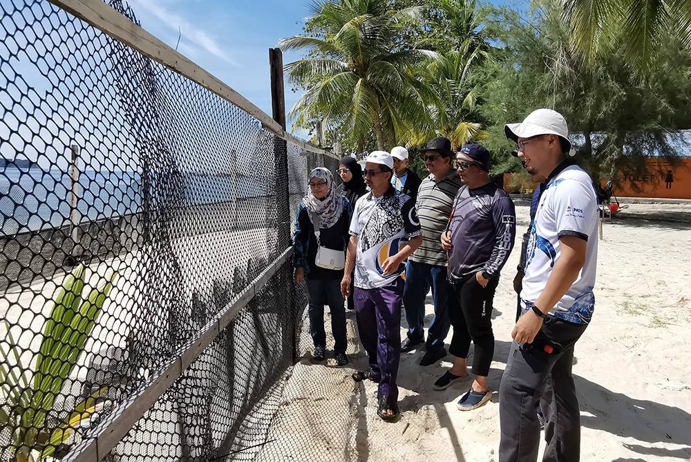 Mohd Uzair (kanan) memberi penerangan di salah satu kawasan konservasi penyu di Pusat Taman Laut di Pulau Redang.