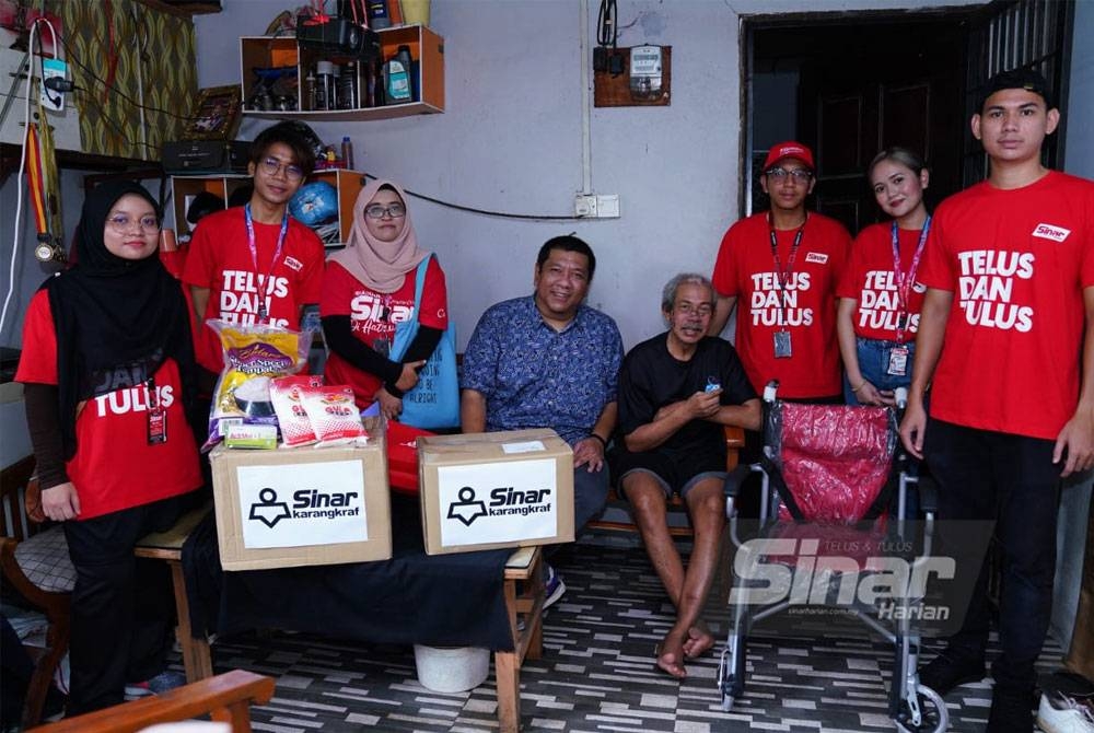 Nik Justin (empat dari kiri) menyerahkan kerusi roda dan sumbangan barangan keperluan harian kepada Razali di rumahnya di Kampung Bukit Kuda pada Rabu. - FOTO MOHD HALIM ABDUL WAHID