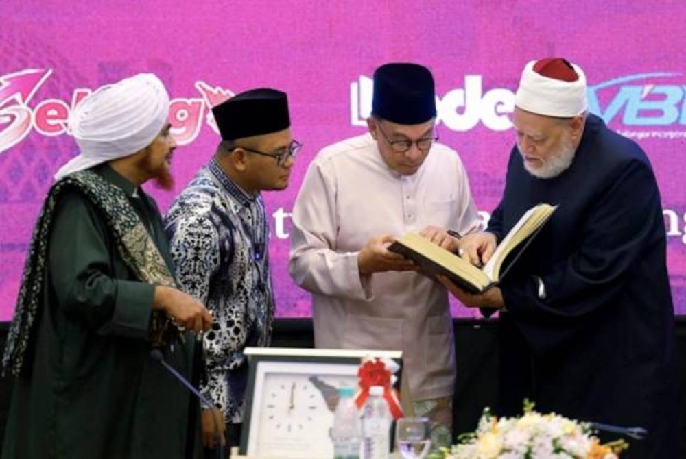 Anwar menerima senaskhah al-Quran daripada bekas Mufti Agung Mesir, Profesor Ali Jumah (kanan) pada Majlis Muzakarah dan Umara sempena Festival Turath Islami Selangor 2023 pada Khamis. - Foto Bernama