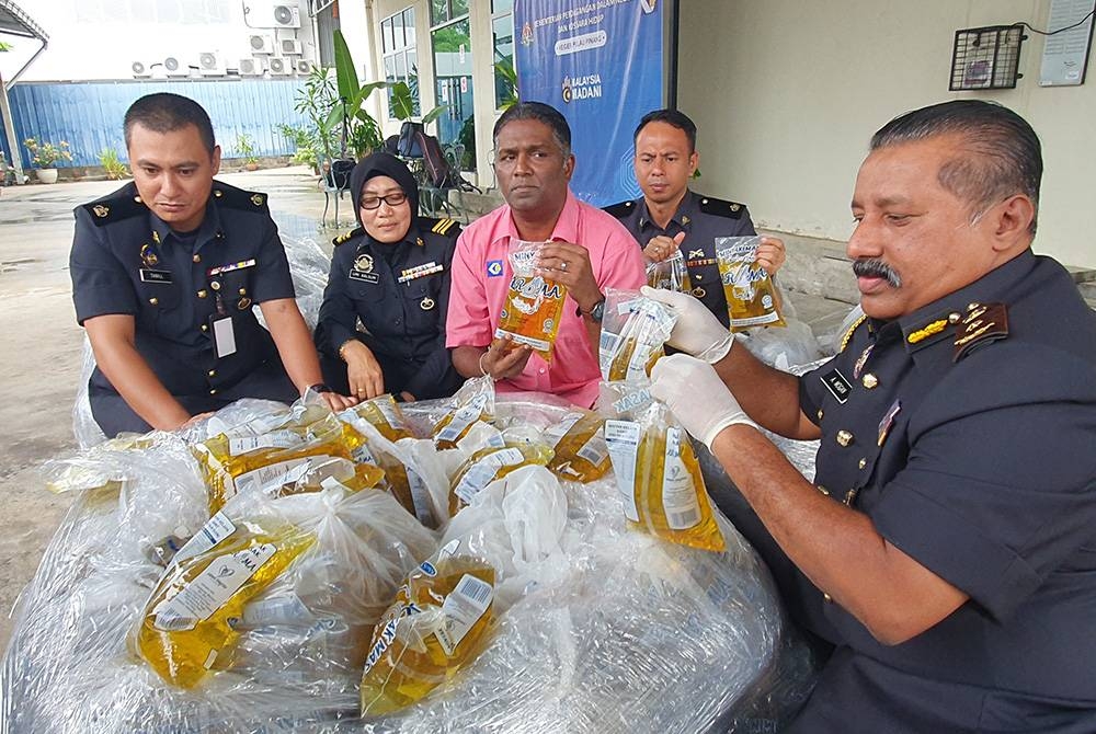 Jegan (tiga dari kiri) menunjukkan minyak masak paket bersubsidi yang dirampas pada sidang akhbar di Stor Eksibit KPDN, Bukit Minyak pada Jumaat.