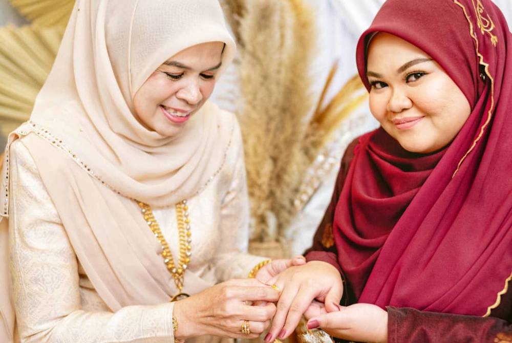 Julia (kiri) ketika menyarungkan cincin di jari Nurfahana pada majlis pertunangan 24 April lalu.