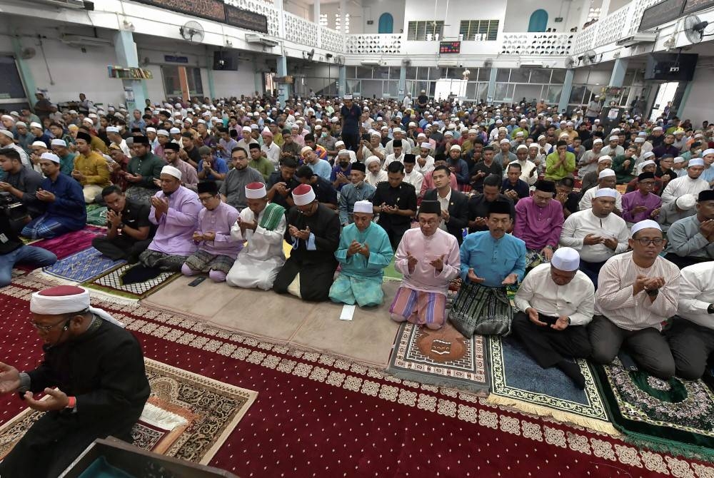 Anwar (lima dari kanan) aminkan doa selepas tunaikan solat Jumaat di Masjid An-Naim Kampung Jalan Kebun hari ini. - Foto Bernama