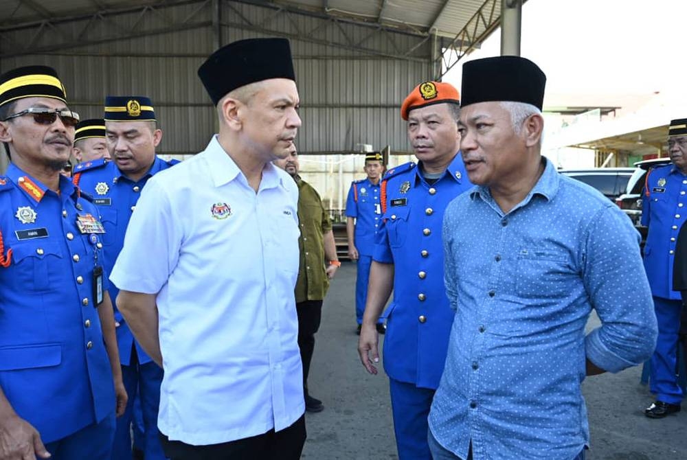 Armizan (dua dari kiri) dan Mohamad (kanan) bersama pasukan APM ketika menyambut ketibaan jenazah Allahyarham Awang Askandar di pekarangan MAS Kargo, Kota Kinabalu.