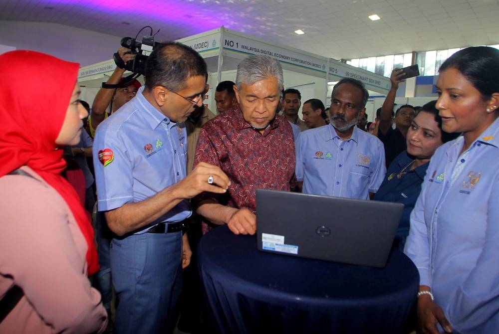 Ahmad Zahid (tiga dari kiri) mendengar penerangan daripada Mohammed Azman ketika melawat ruang pameran pada Karnival Kerjaya MyFutureJobs dan SKSSR 2023 di Bagan Datuk pada Ahad.