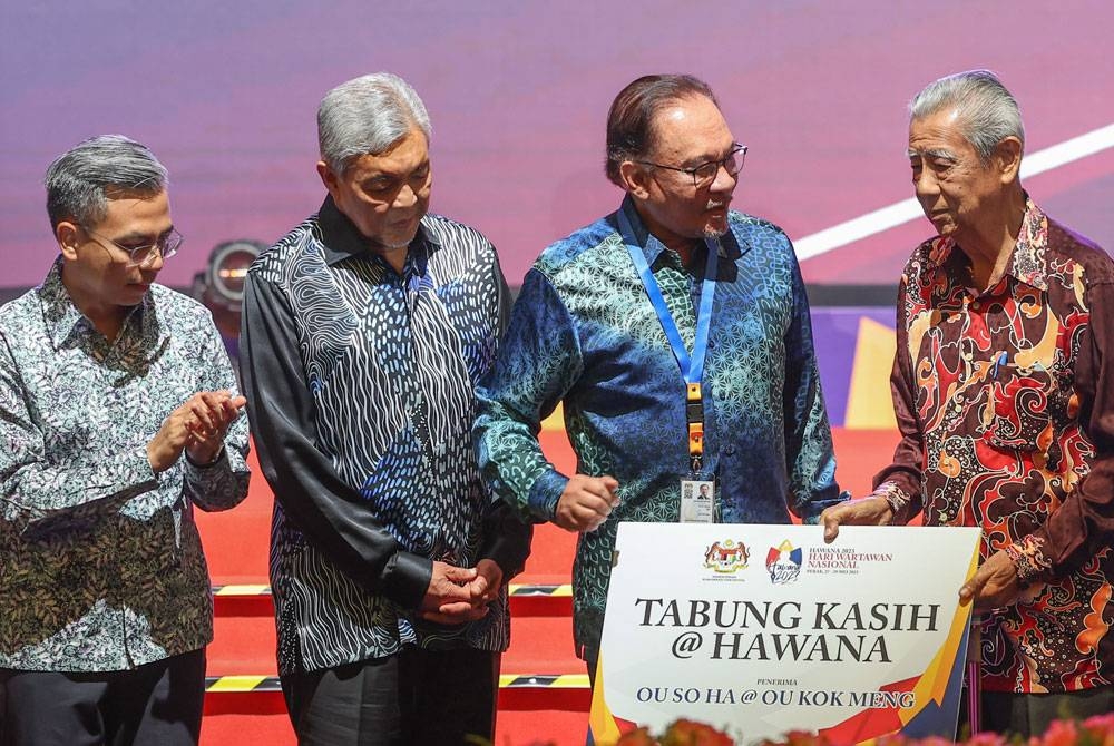 Anwar menyampaikan sumbangan Tabung Kasih Hawana kepada Ou So Ha @ Ou Kok Meng (empat dari kiri) pada kemuncak sambutan Hari Wartawan Nasional (Hawana) 2023 di Hotel Casuarina, Meru pada Ahad. - Foto Bernama