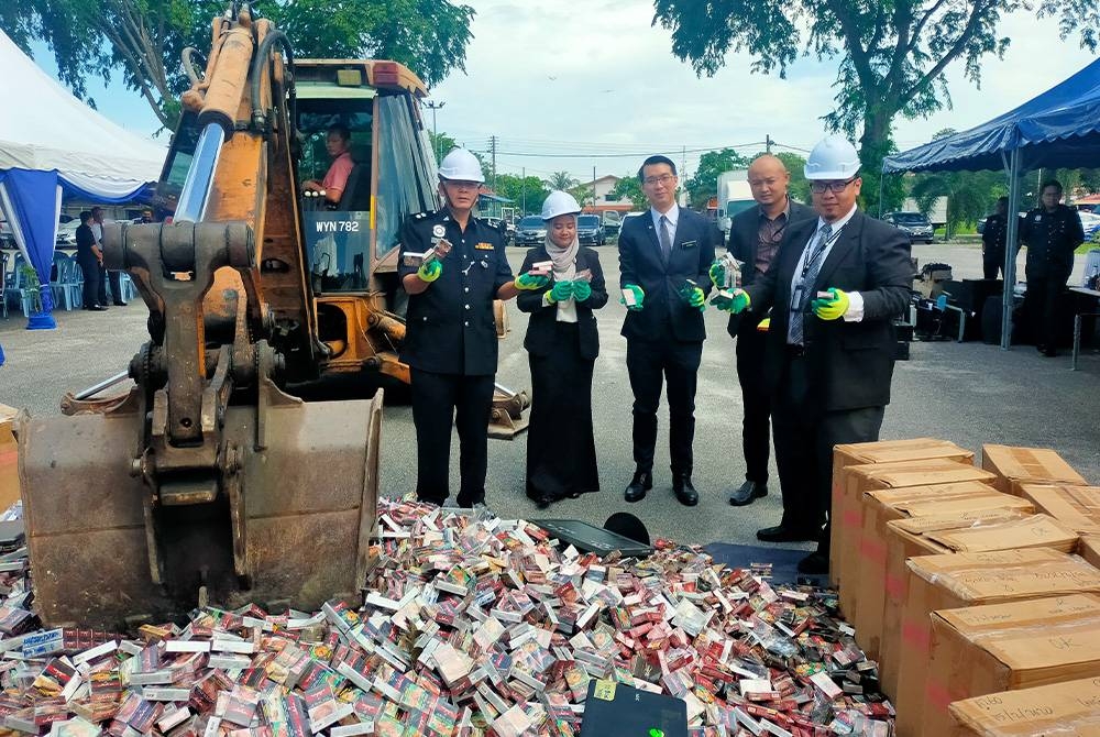 Mohd Khairi (kiri) menunjukkan barangan rampasan kes kontraban iaitu rokok seludup yang akan dilupuskan selepas majlis gimik pelupusan di Balai Polis Kapar, Klang, Selangor pada Isnin.