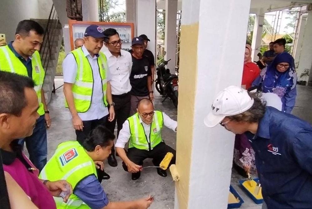 Mohd Jafni (berdiri, dua dari kiri) menyaksikan gimik kerja-kerja mengecat flat Kangkar Pulai oleh Pandak (duduk, kanan) dan Mohd Hafiz duduk, kiri) pada Selasa.