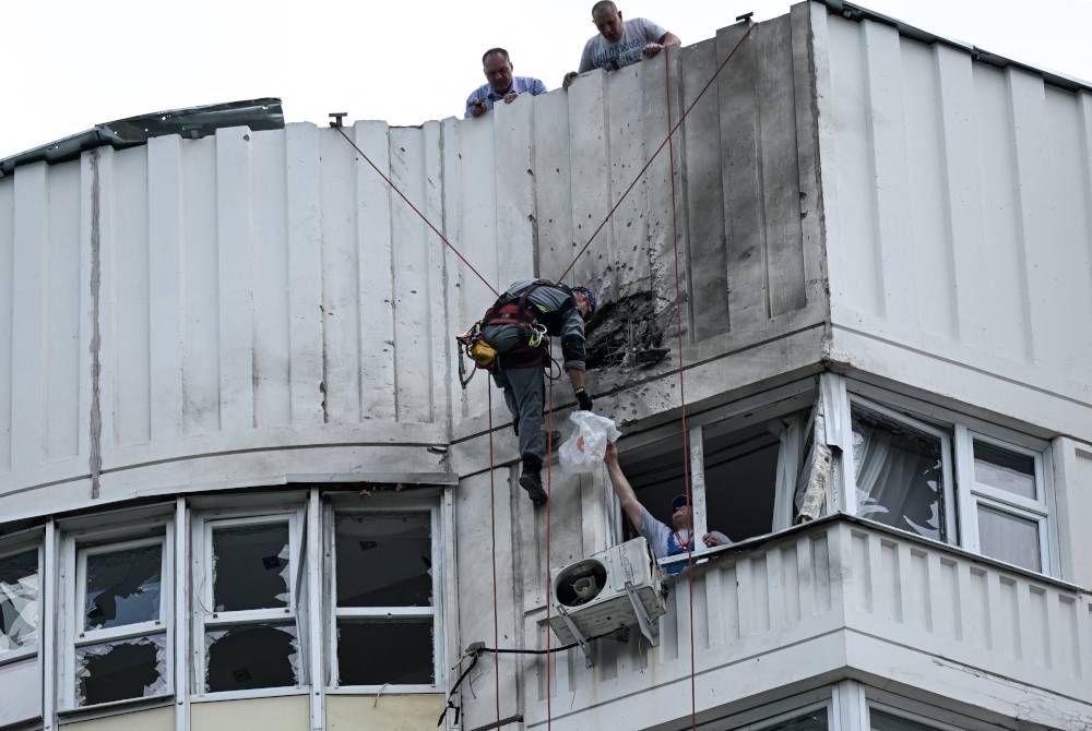 Pakar memeriksa bahagian bangunan apartmen yang musnah akibat serangan dron di Moscow. - Foto AFP