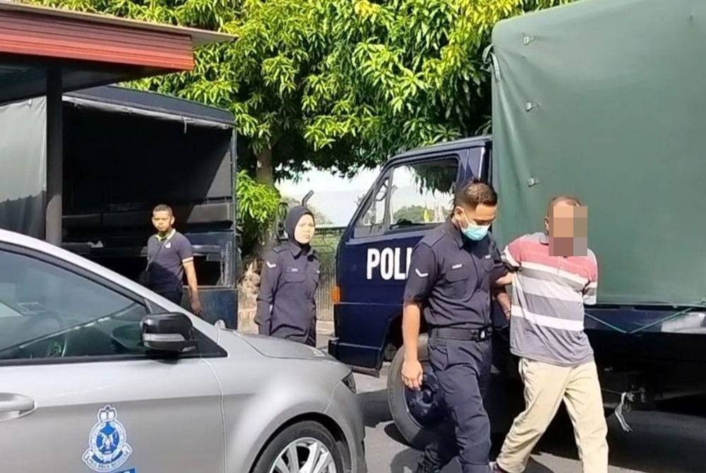 Tertuduh ketika diiringi anggota polis sebaik tiba di pekarangan mahkamah pada Khamis.