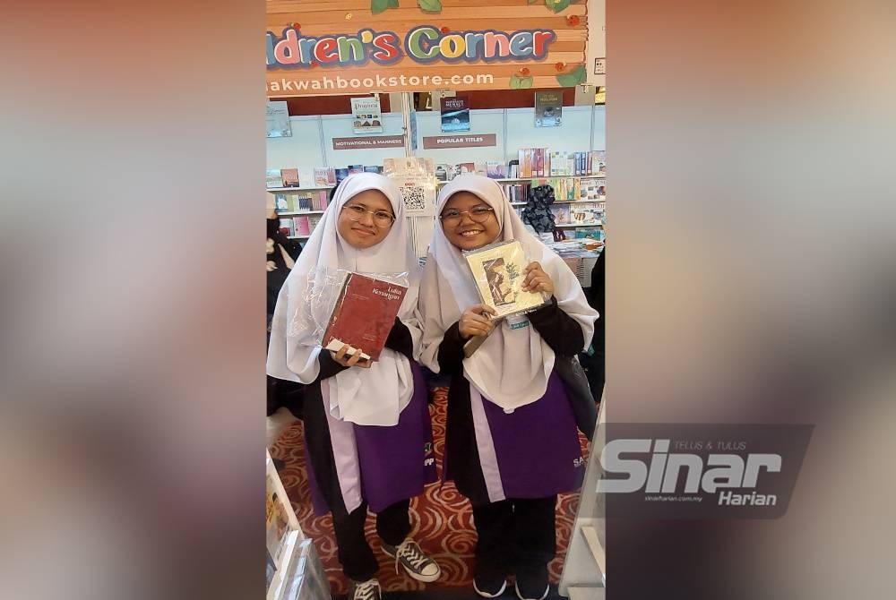 Dari kiri: Fatma Syahira dan rakannya Siti Norizzatul Nazera Mohamad Bajuri menunjukkan buku yang dibeli di reruai Karangkraf.