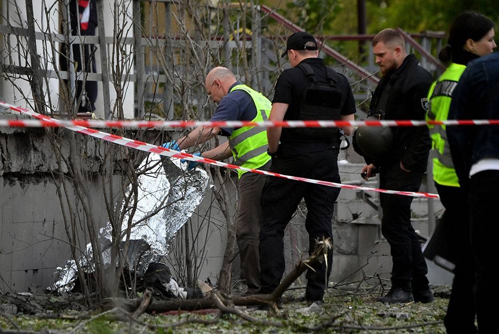 Polis memeriksa mayat wanita yang maut dalam serangan Rusia di Kyiv pada Khamis. - Foto AFP