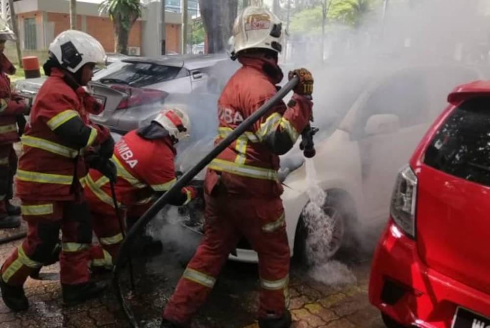 Anggota Bomba dan Penyelamat sedang memadamkan kebakaran dua kenderaan terbakar di kawasan parkir di hadapan Kompleks PKNS, Shah Alam pada Khamis.