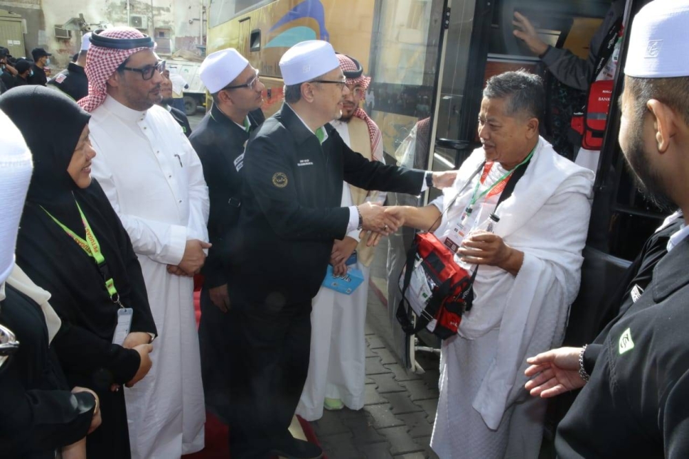 Syed Saleh (tiga dari kanan) menyambut jemaah yang tiba di Makkah pada pagi Jumaat.