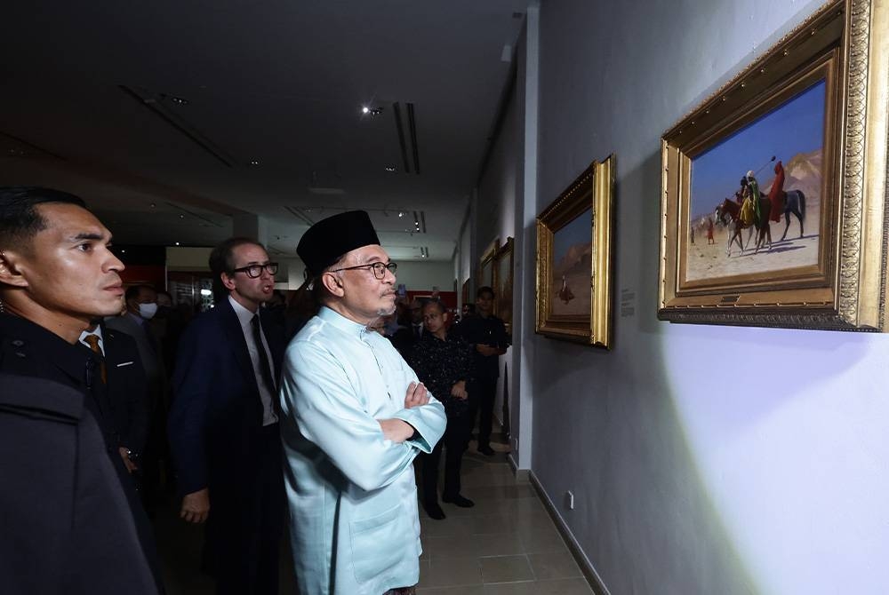 Anwar diberi penerangan oleh Pakar lukisan Oriantalis Claude Piening (kanan) ketika melawat pameran selepas Perasmian Pameran &#039;Orientalism Paintings&#039; di Muzium Kesenian Islam Kuala Lumpur pada Jumaat. - Foto Bernama