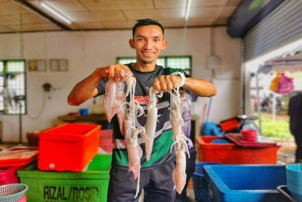 Syed Ahmad Aizuddin menunjukkan antara sotong yang dijual di premis jualan di Kampung Durian Burung, di Kuala Terengganu.