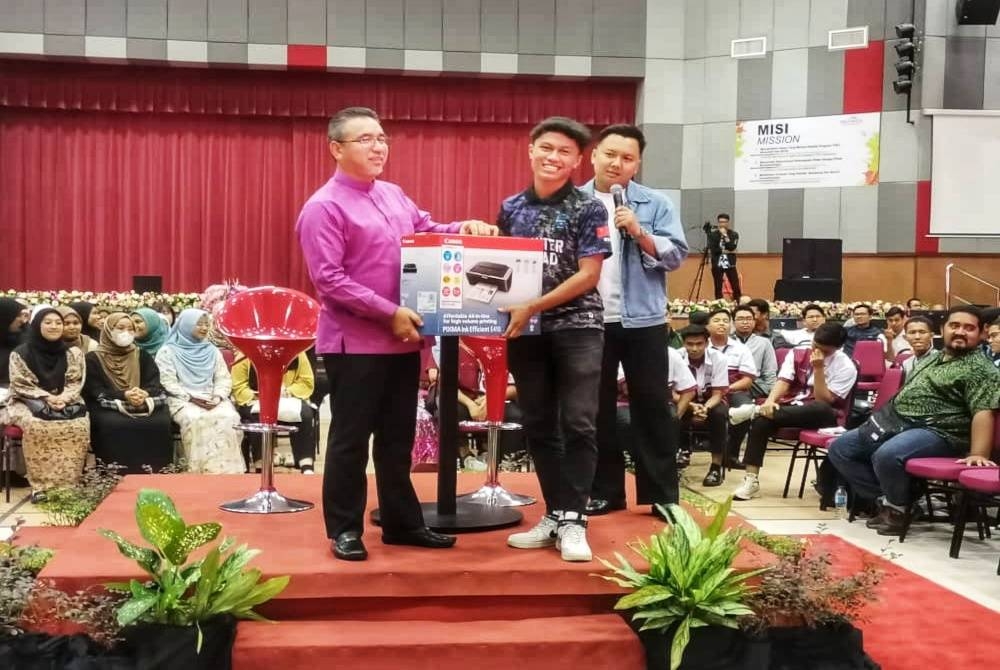 Adly (kiri) menyampaikan hadiah cabutan bertuah kepada pelajar di sesi Town Hall bersama mahasiswa negeri Kedah di Politeknik Sultan Abdul Halim Mu'adzam Shah (Polimas) pada Ahad.