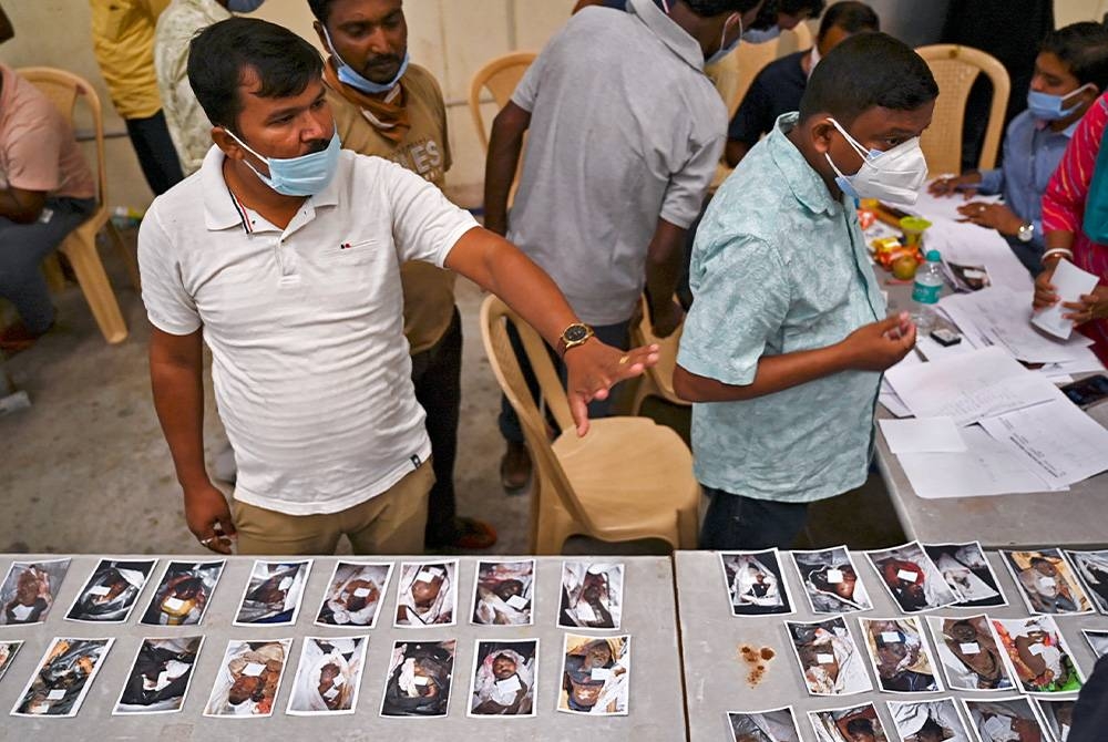 Gambar mangsa dipaparkan untuk waris keluarga yang menunggu di rumah mayat sementara. - Foto: AFP