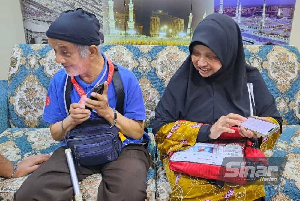 Muhammad Bukhara dan Siti Aidah menunjukkan keupayaan mereka mendengar pesanan mesej melalui telefon bimbit.