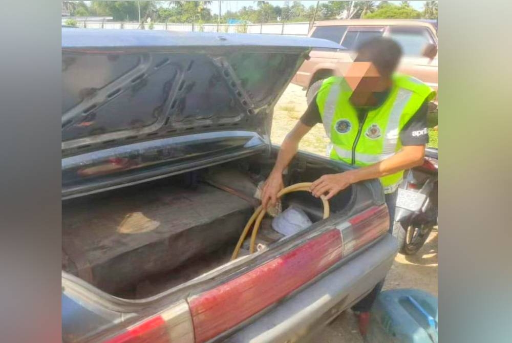 Anggota penguat kuasa KPDN Kelantan memeriksa tangki tambahan yang diubahsuai pada Proton Iswara untuk mengisi minyak petrol yang diseludup.