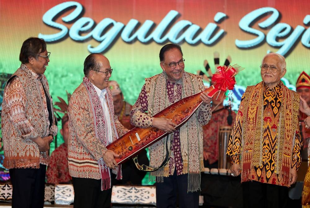 Anwar (dua dari kanan) mencuba alat muzik tradisional Sarawak iaitu ‘sape’ majlis Perayaan Gawai Dayak 2023 di Pusat Konvensyen Borneo Kuching malam ini. - Foto Bernama