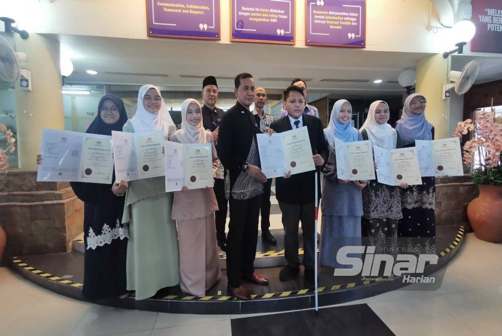 Abdul Muie (tengah) bergambar bersama calon cemerlang SPM 2022 selepas mengumumkan keputusan peperiksaan itu di Jabatan Pendidikan Negeri Terengganu di Kuala Terengganu pada Khamis.