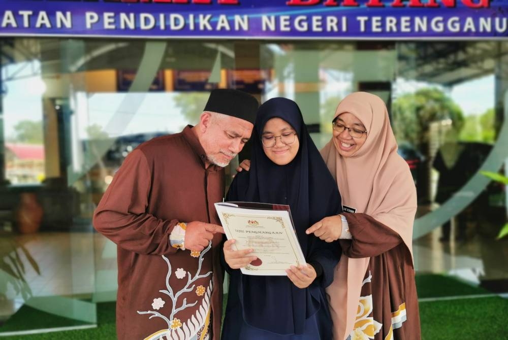 Nur Nadiatul Syakila (tengah) bersama ibunya, Che Rohaini dan bapanya, Mohd Razif selepas menghadiri majlis pengumuman keputusan peperiksaan SPM Terengganu 2022 di Jabatan Pendidikan Negeri Terengganu (JPNT), di Kuala Terengganu, pada Khamis.