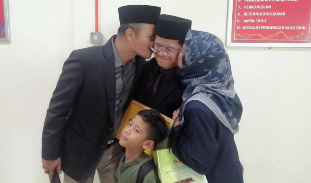 Danial (tengah) ditemani ibu bapa serta adik ketika mengambil keputusan SPM di SMA MAIWP pada Khamis.