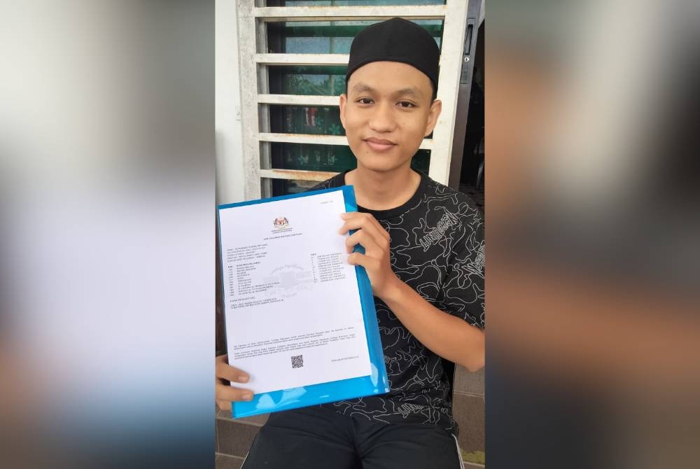 Muhammad Shahril menunjukkan keputusan SPM yang diterima daripada guru yang menghantar keputusan itu di rumahnya pada Khamis.