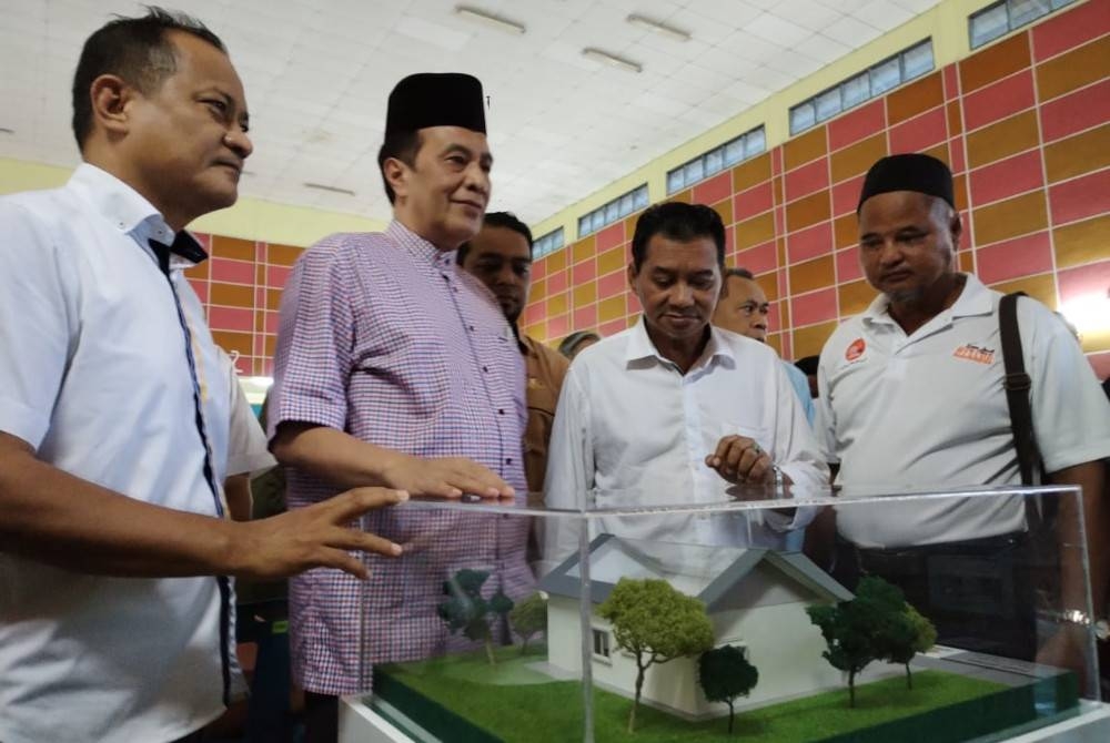 Husam (dua dari kiri) melihat model rumah SPNB pada Majlis Ramah Mesra dan Taklimat dengan Generasi Kedua Felda Bukit Ramun dan Sungai Sayong di Dewan Semai Bakti Felda Bukit Ramun, Kota Tinggi pada Jumaat.